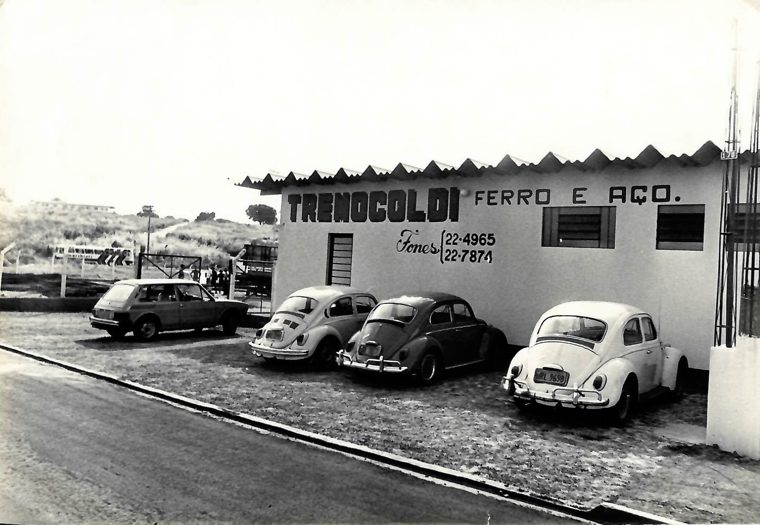 Fachada da Tremocoldi em 1981: prédio branco com letreiro pintado à mão, três Fuscas e uma Brasília estacionados