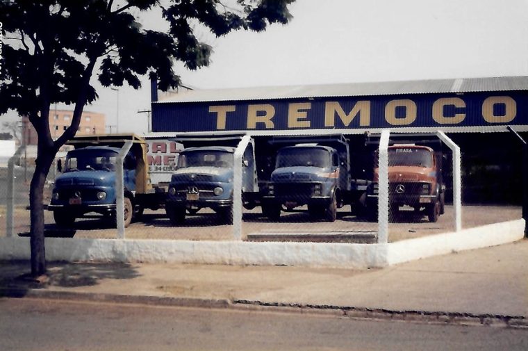 Quatro caminhões Mercedes-Benz sob o galpão da Tremocoldi, com letreiro azul e amarelo, em 1994