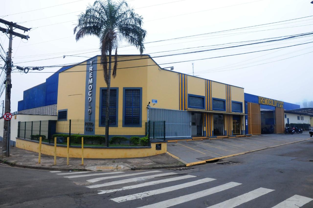 Fachada da Tremocoldi vista da esquina, com o letreiro no galpão e uma palmeira em frente